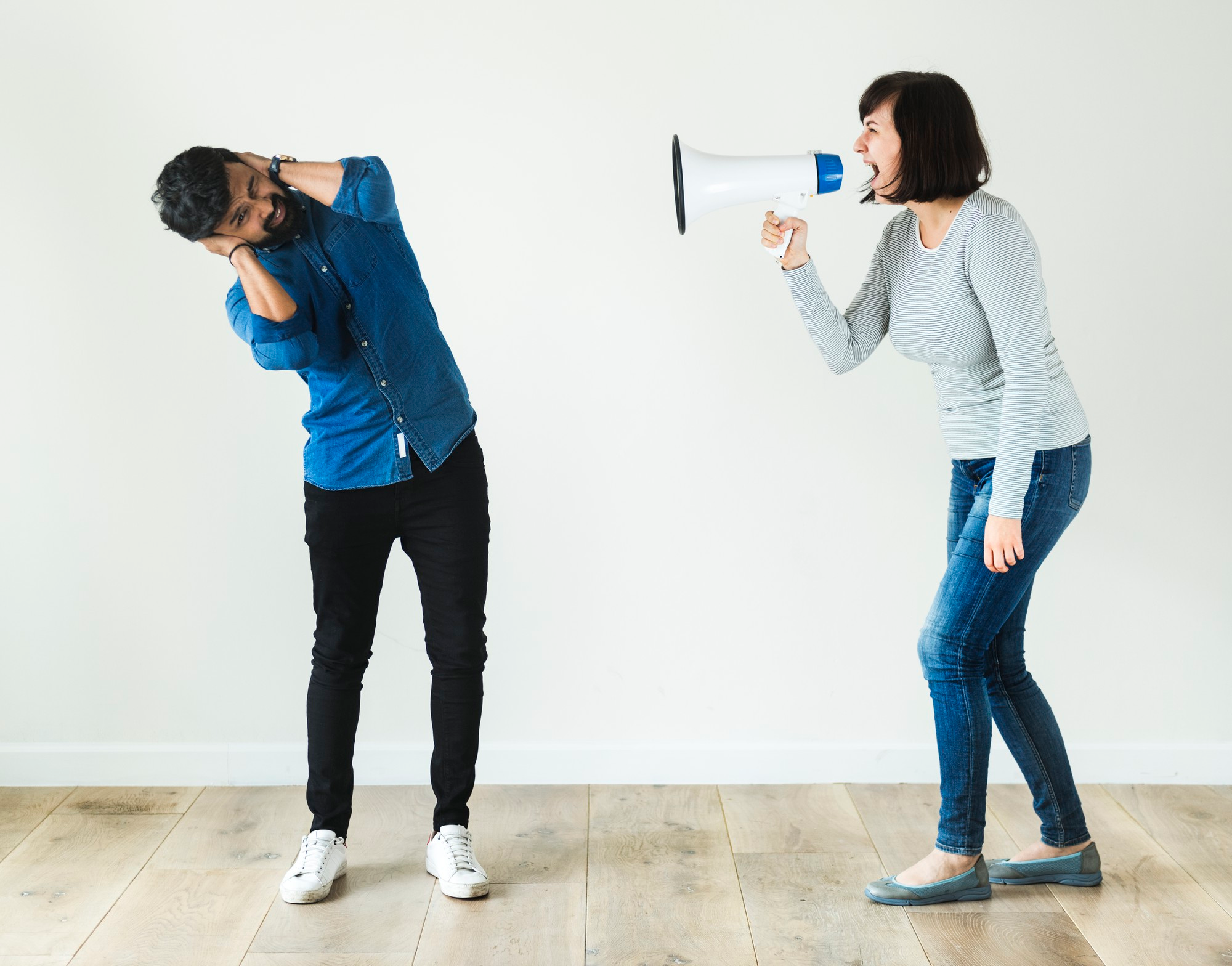 Femme hurlant dans un mégaphone en direction de son copain. Elle veut qu'il comprenne qu'il doit faire le ménage autant qu'elle